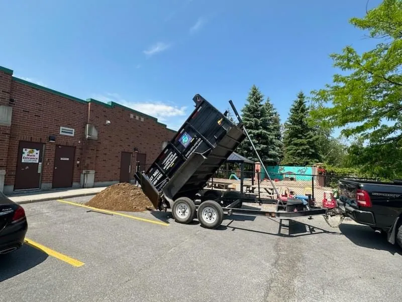 OneBluePlanet dump trailer delivering landscape material at a commercial property