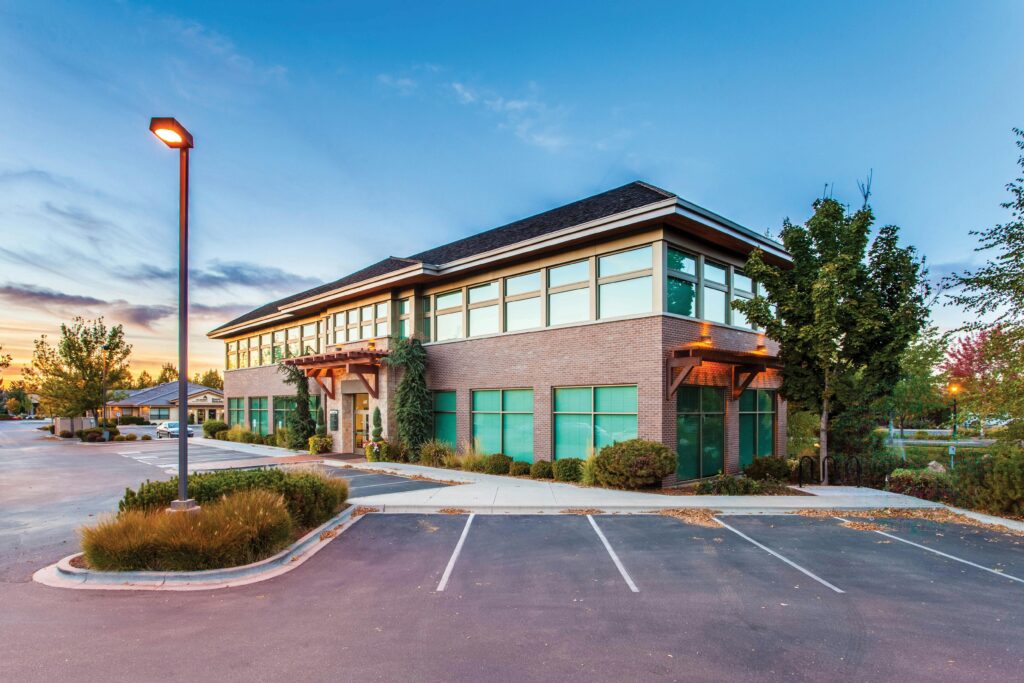 What My Year-Round Groundskeeping Program Does for High-Traffic Commercial Sites in Ottawa A modern two-story office building in Eagle, ID, captured at sunset with a clear blue sky.